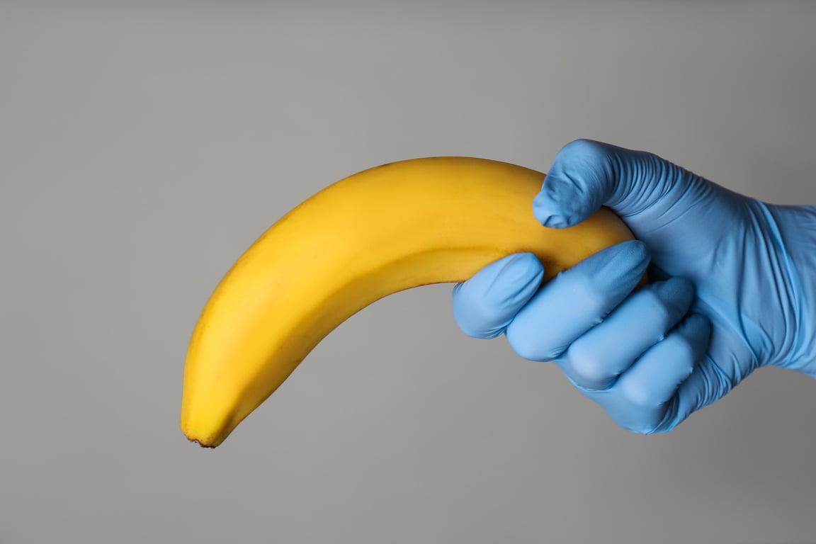 Doctor Holding Banana Symbolizing Male  Organ on Grey Background, Closeup. Potency Problem